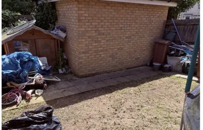 Garden ground cleared of weeds beside a brick outbuilding